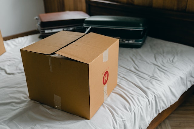 a moving box and suitcases sitting on a bed