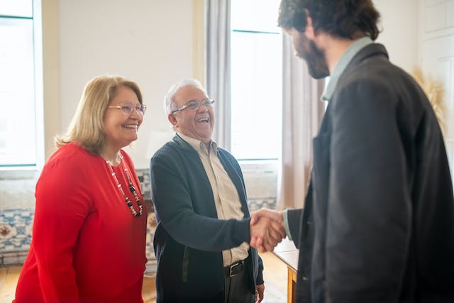 three people in suits shaking hands in a home