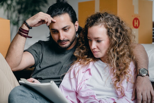 two people on a couch reading papers with boxes behind them